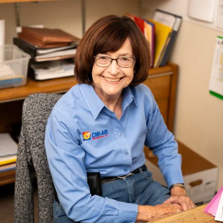 CMI office worker wearing glasses, smiling at her desk